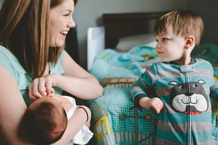 Smiling mum carrying baby besides an older child